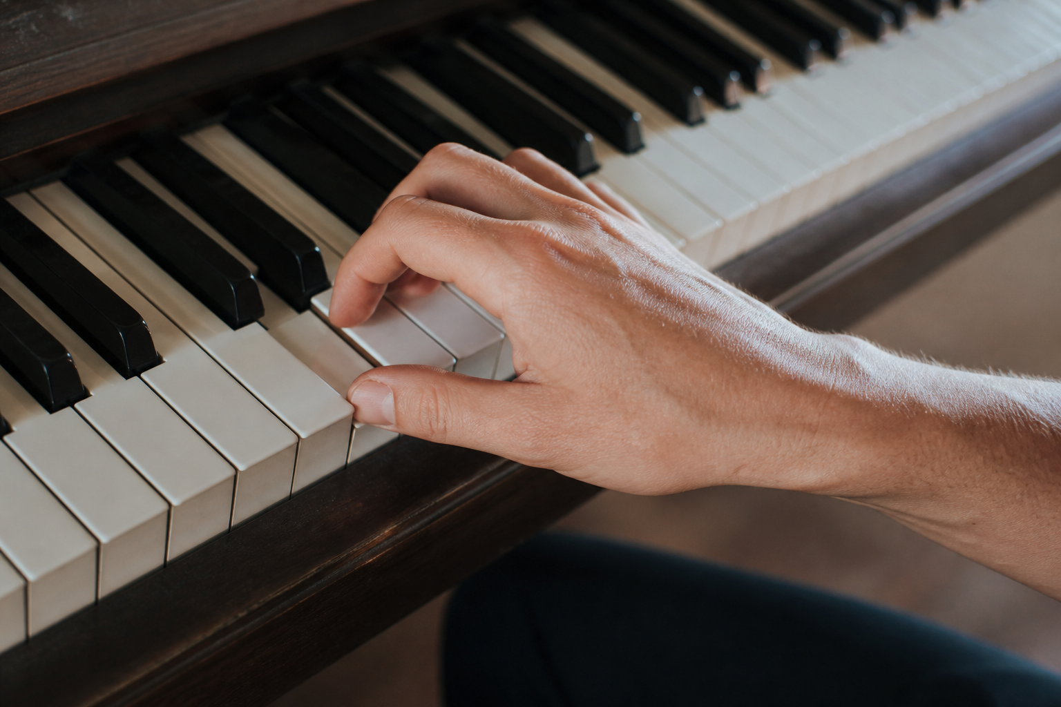Close up of pianist hands on keys showing correct rounded finger position with elevated knuckles